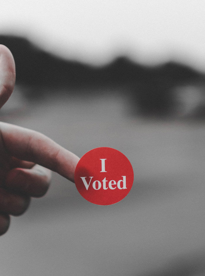 Hand holding 'I Voted' sticker