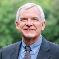 Man in suit outdoors with greenery