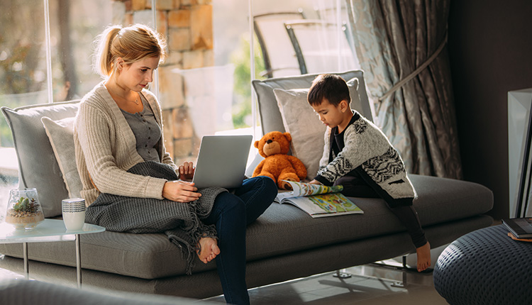 Woman working on laptop with child.
