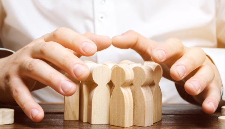 Hands protecting wooden figures together