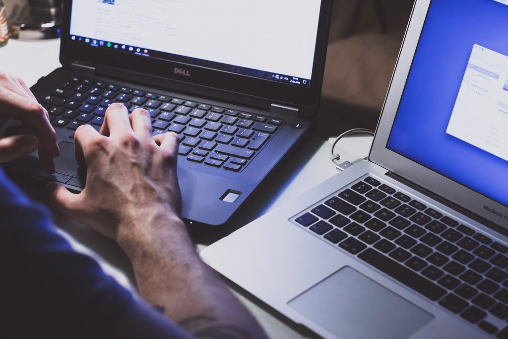 Two laptops on a desk, typing.