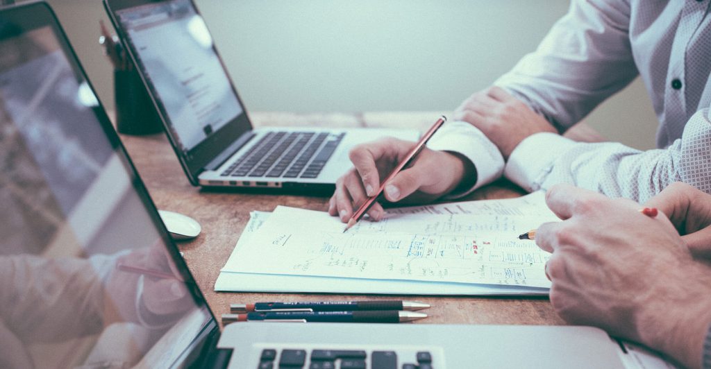 People discussing documents and laptops.