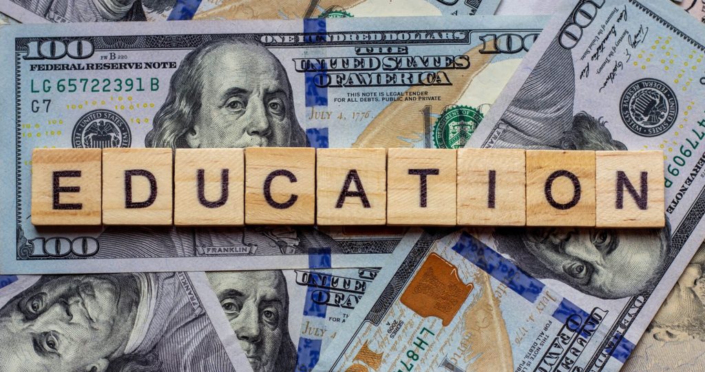 Wooden blocks spell 'EDUCATION' on money.