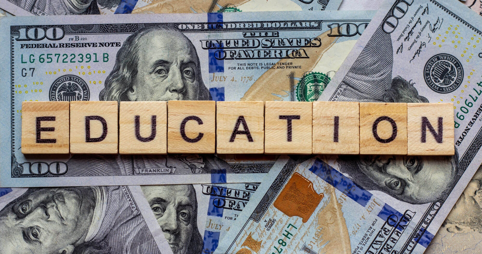 Wooden blocks spell 'EDUCATION' on money.