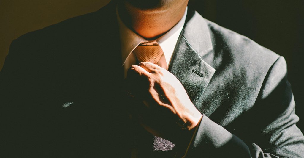 Man adjusting tie in suit