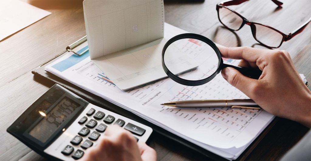 Calculator, documents, magnifying glass, pen.