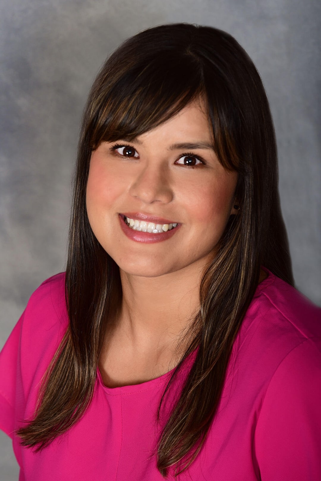 Woman in pink top, neutral background.